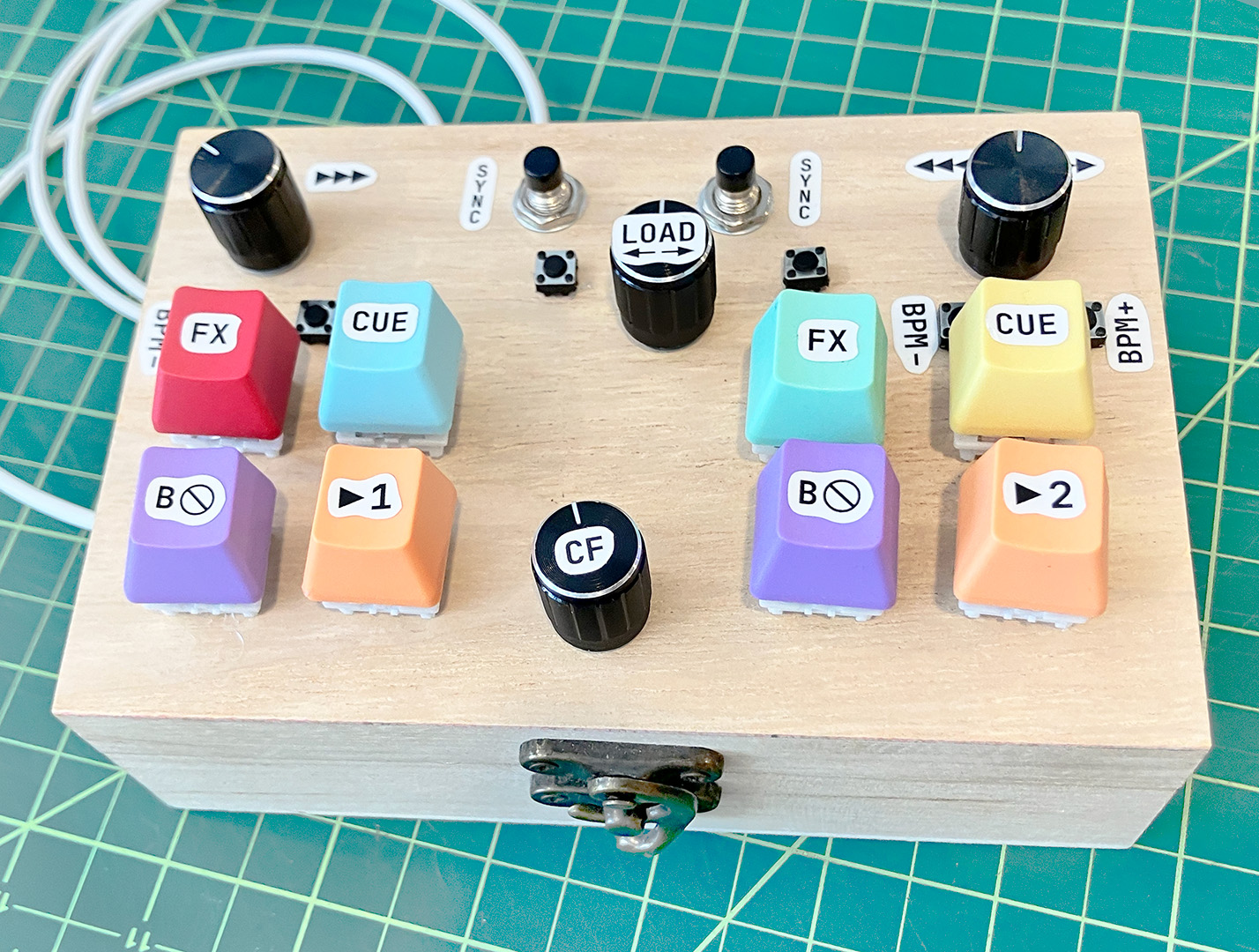 A custom-made DJ controller, with various knobs and multicolor keys installed in a wooden box, with a sticker label on each button