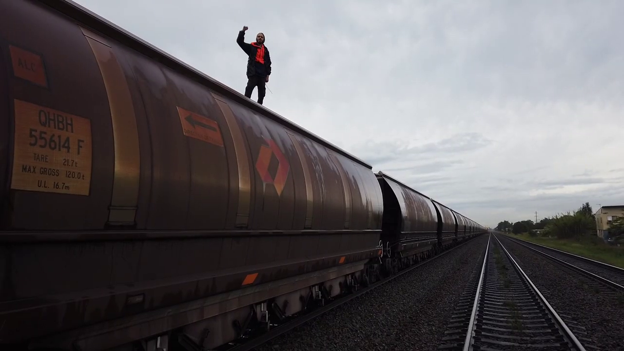 A man stands on top of a fuel train with his fist raised defiantly