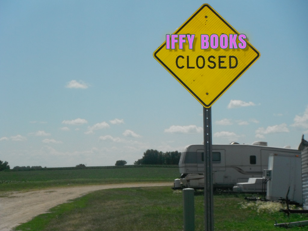 A yellow sign in front of a country road and an RV. The sign says "Iffy Books Closed," with "Iffy Books" superimposed in pink text with blue and black outlines.