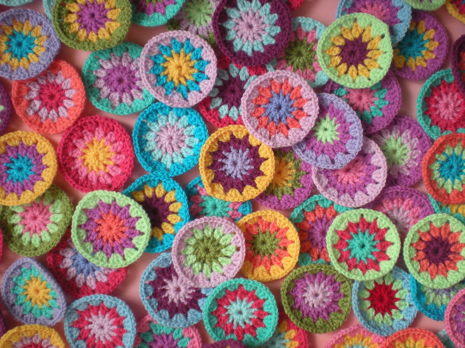 A photo of several dozen colorful crocheted circles scattered on a table