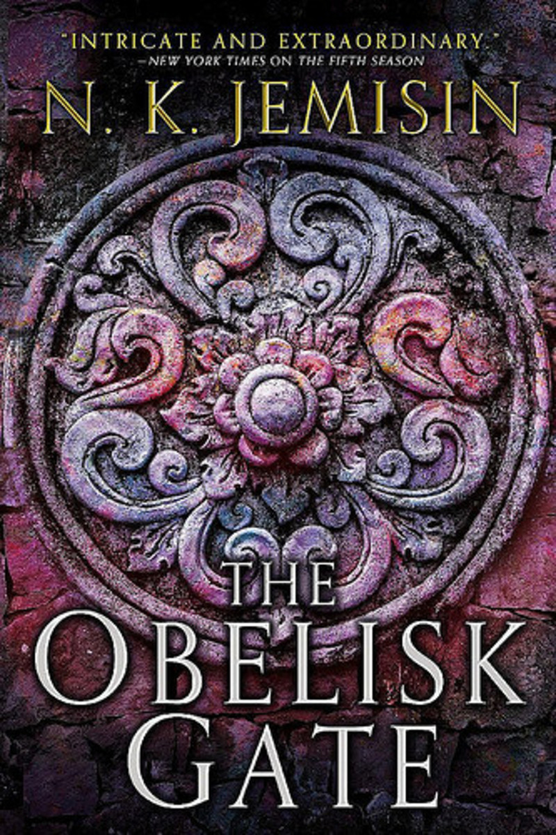 Cover of the book 'The Obelisk Gate' by N.K. Jemisin, with a closeup photo of a red-tinted stone carving of a flower surrounded by stylized leaves in a circle.