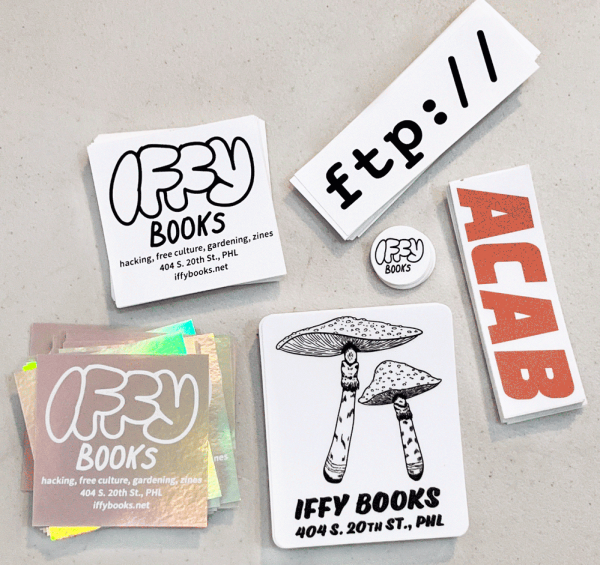 Six stickers from Iffy Books: one with a reflective background, one with white on black, one with illustrations of mushrooms, a one-inch circle, one that says "ftp://" and one that says ACAB in a style resembling a familiar logo.