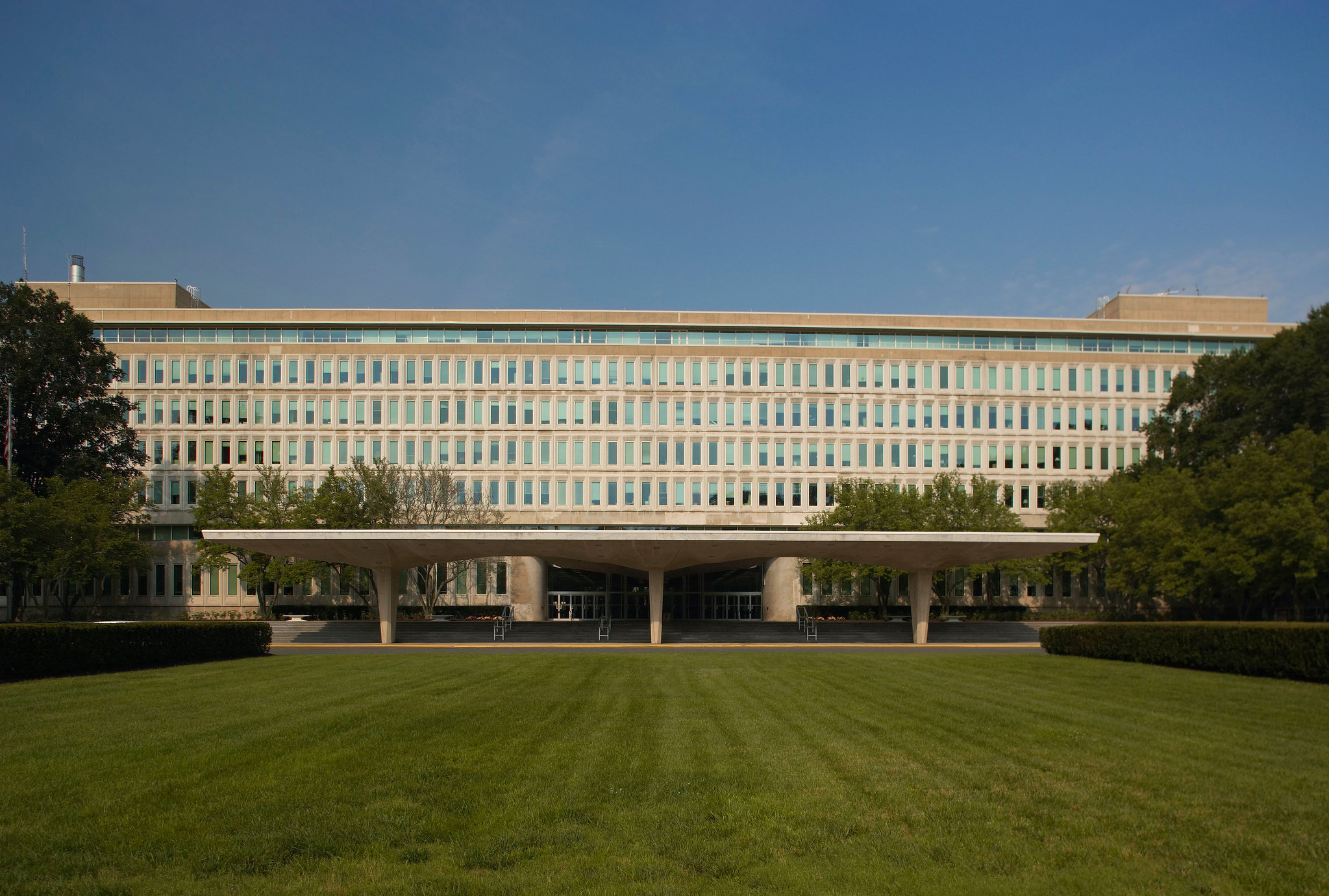 A photo of CIA headquarters: a wide office building with a retro concrete awning and a large lawn