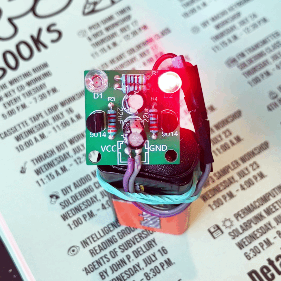 Animated GIF of a small circuit board with two blinking LED lights, two transistors, two capacitors, and four resistors
