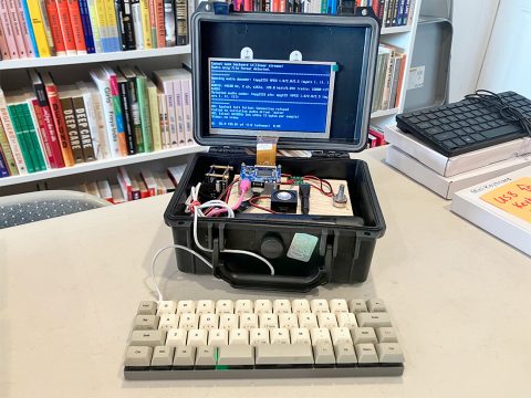 Photo of a cyberdeck, a.k.a. a do-it-yourself laptop, at Iffy Books. There's a mini keyboard attached, and there's an internet radio station playing onscreen