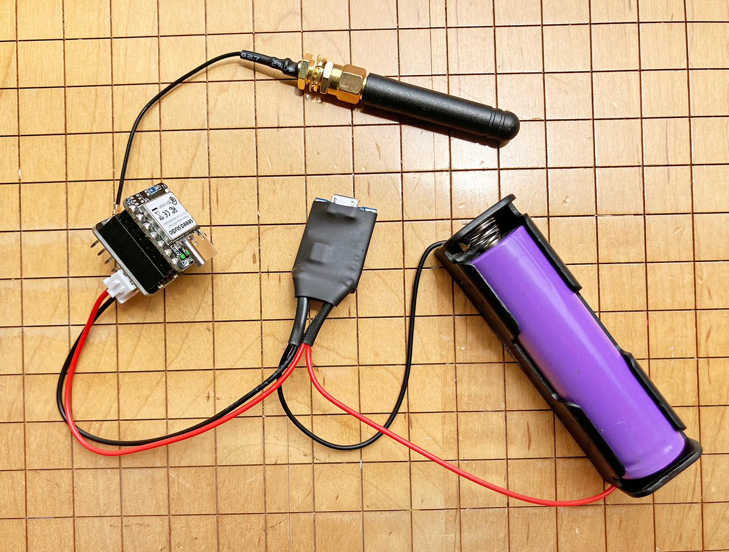 Photo of a purple TP4056 lithium-ion battery connected to a TP4056 charge controller and a PH2.5 connector, which is plugged into a LoRa radio node with the green power light on